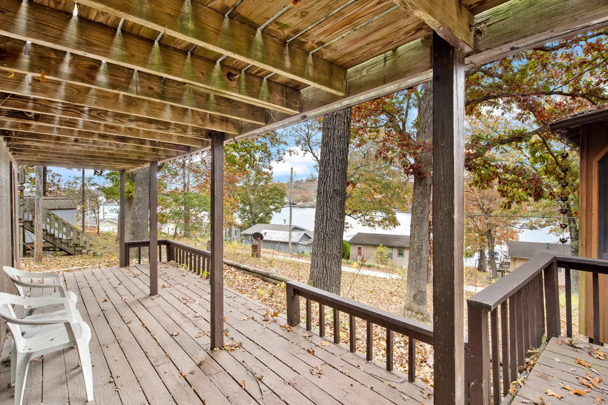 A wooden deck surrounded by lush trees and an open view, ideal for relaxing outdoors, social gatherings, or simply soaking in nature. The space suggests an inviting transition from the private home into the broader lakeside environment.