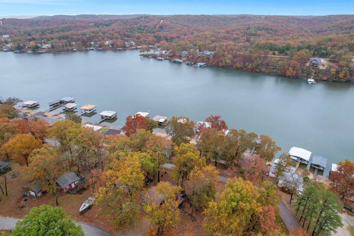 This image features calm lake waters bordered by striking autumn foliage and scenic hills, with docking areas hinting at lakeside activities. The peaceful setting is complemented by tranquil morning light, emphasizing the natural beauty and accessibility of the lake.