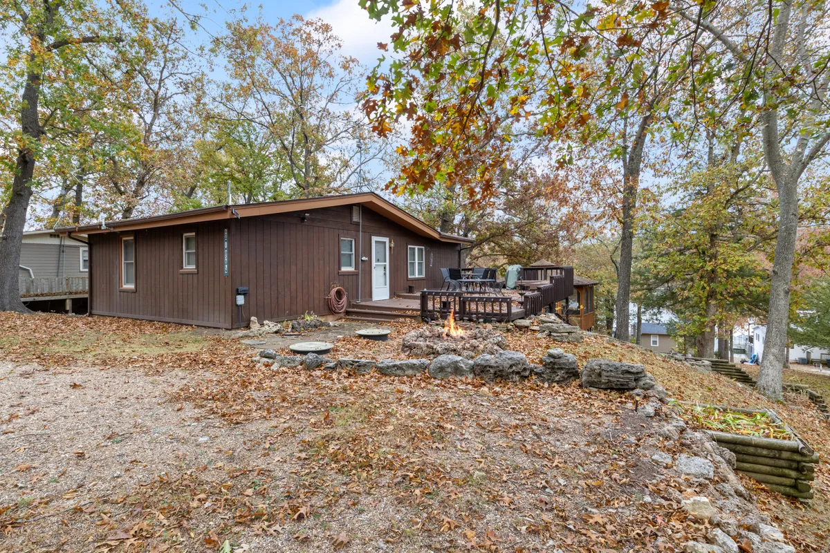 This image shows the wooden exterior of the house with a cozy fire pit and a spacious deck, all set amidst autumn leaves and lush trees. The fire pit area is inviting, encouraging gatherings and relaxation in a peaceful natural setting, while the structure itself conveys privacy and seclusion.