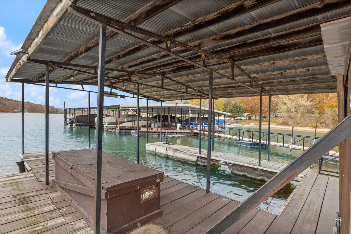 A peaceful lake scene featuring a private dock with boats moored alongside, a rustic storage box, and the calm water surface reflecting the light. The dock is easily accessible and the scene exudes a sense of relaxation and leisure by the water.