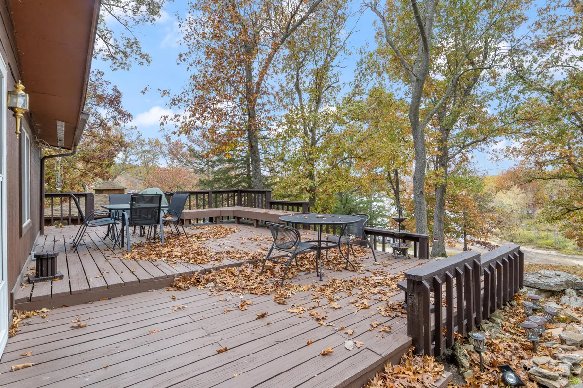 A tranquil deck furnished with comfortable outdoor furniture, set against striking fall foliage and open sky. The railing frames expansive views, making it ideal for both social gatherings and quiet moments of nature observation.