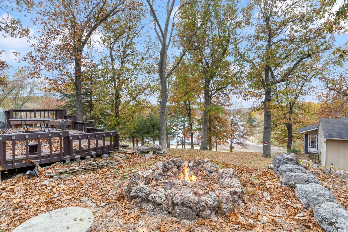 The exterior scene showcases a cozy fire pit on a deck surrounded by trees, inviting guests to enjoy campfire gatherings, outdoor relaxation, or sunset views in a natural setting.