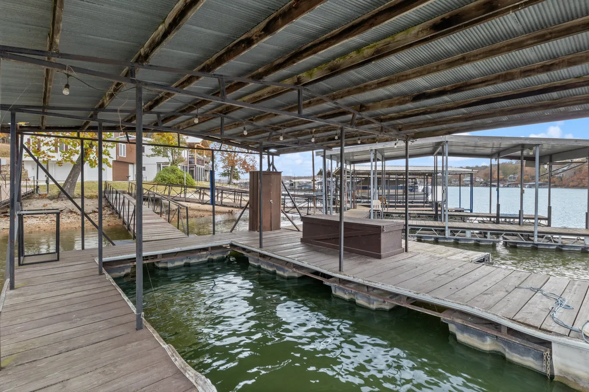 A boathouse structure and wooden docks jutting out into calm water, with the surrounding environment exuding serenity. The dock is sturdy and well-kept, suggesting ample space for boat mooring and lakeside activities.